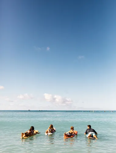 Family surfing at O‘ahu’s Waikīkī Beach in Hawaiʻi 