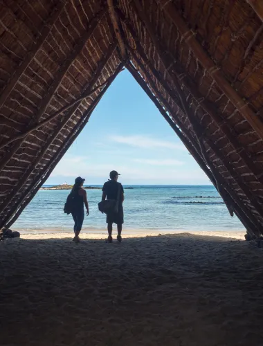 A thatched hut structure at Kaloko-Honokohau National Historical Park framing a view of the beach and ocean