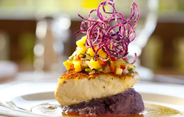Artistically plated dish featuring colorful vegetables and fish
