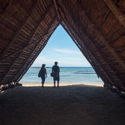 A thatched hut structure at Kaloko-Honokohau National Historical Park framing a view of the beach and ocean