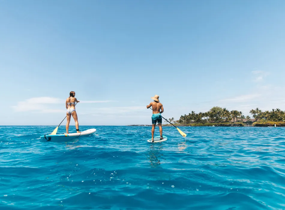 Pair paddleboarding in Kailua Bay, off the coast of Kailua-Kona on the island of Hawaiʻi