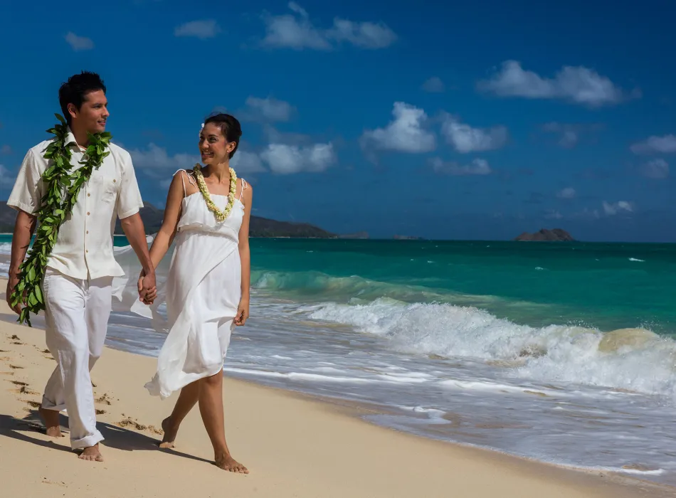 Newlywed couple walking along a beach on Oʻahu in Hawaiʻi