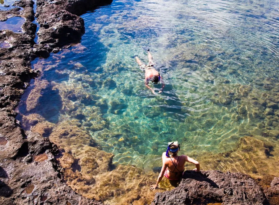 Two snorkelers explore a crystal-clear tide pool.