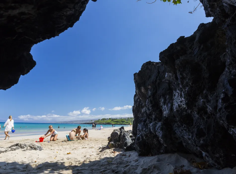 View of Hapuna Beach with white sand, clear blue skies, and families enjoying the shore.