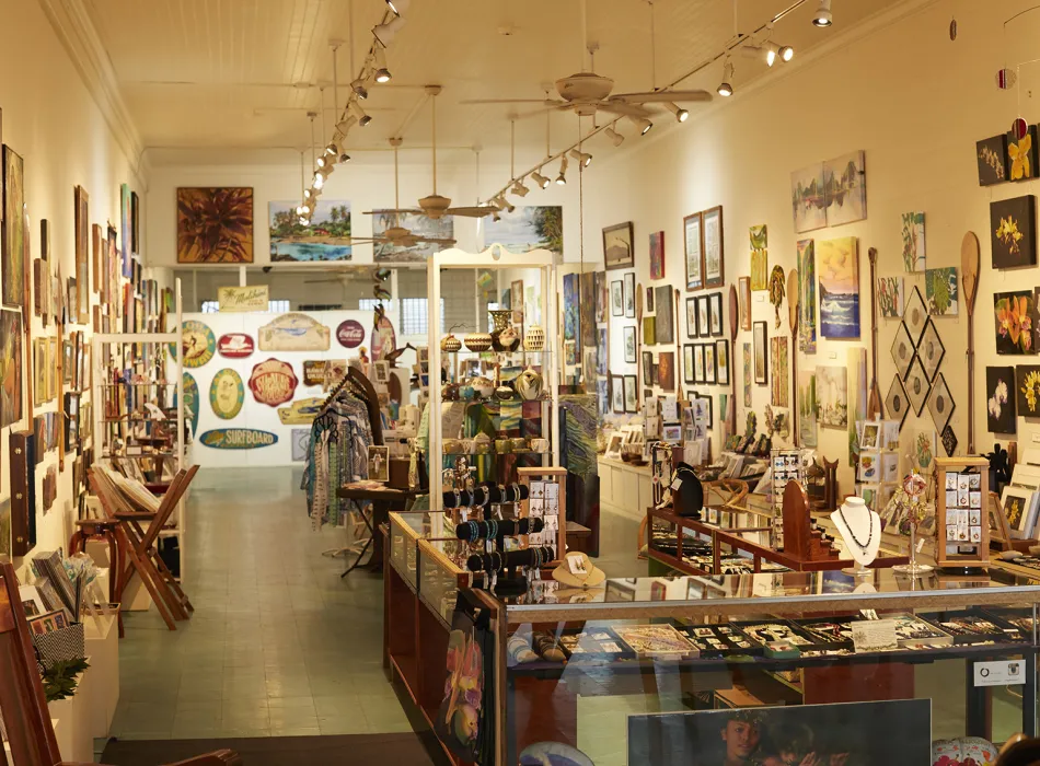 Interior of an art gallery and shop showcasing colorful paintings, jewelry, and locally crafted items on display.
