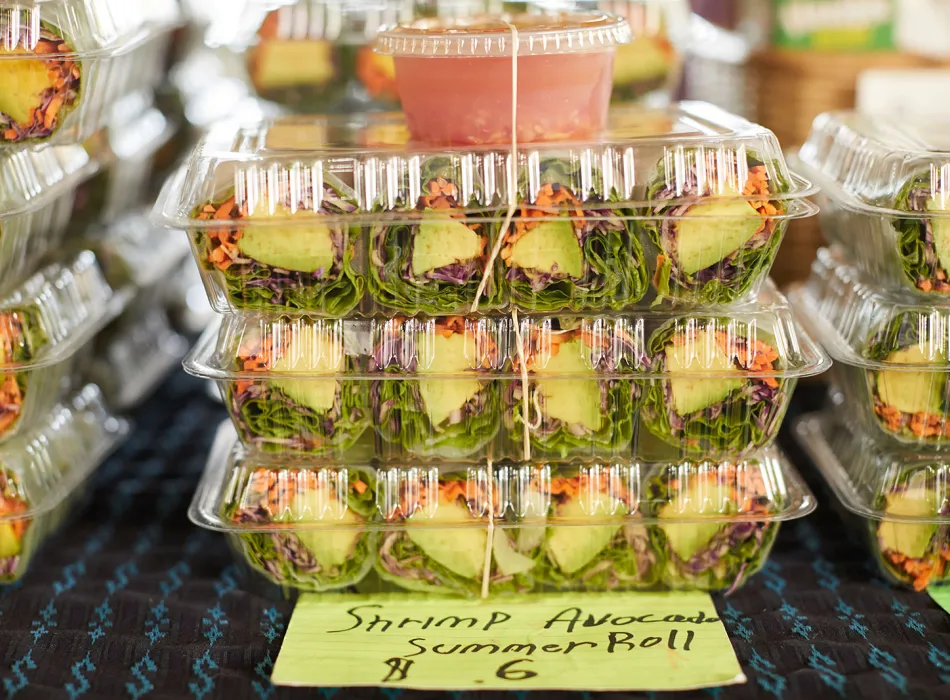 Plastic containers filled with shrimp avocado summer rolls at Hilo Farmers Market, showcasing fresh, local Hawaiian produce.