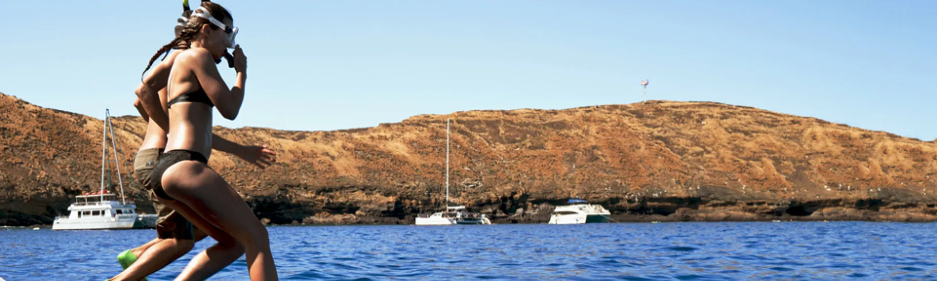 Two snorkelers jumping into the ocean